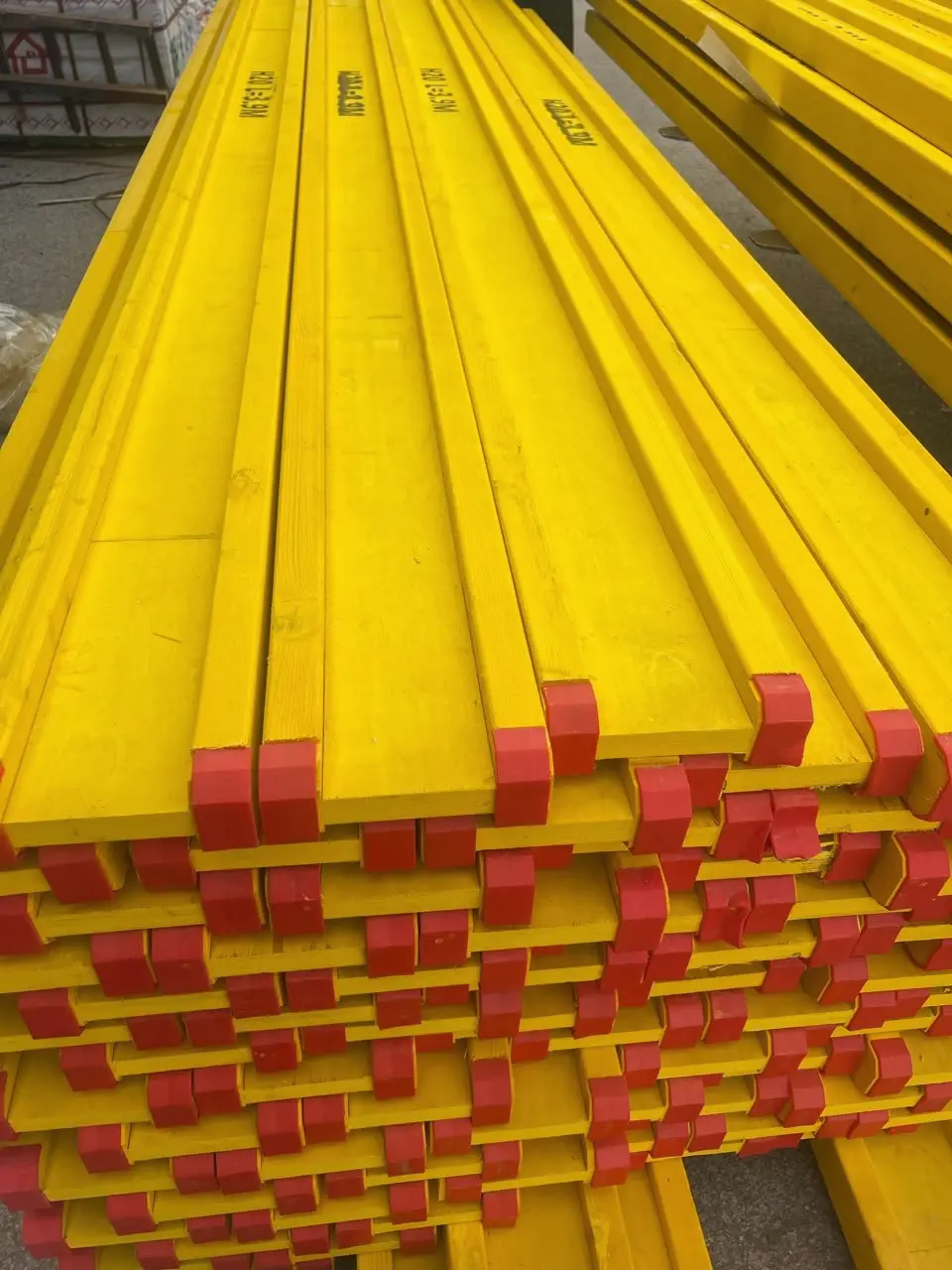 H20 engineered timber beams with red end caps, stacked in the yard